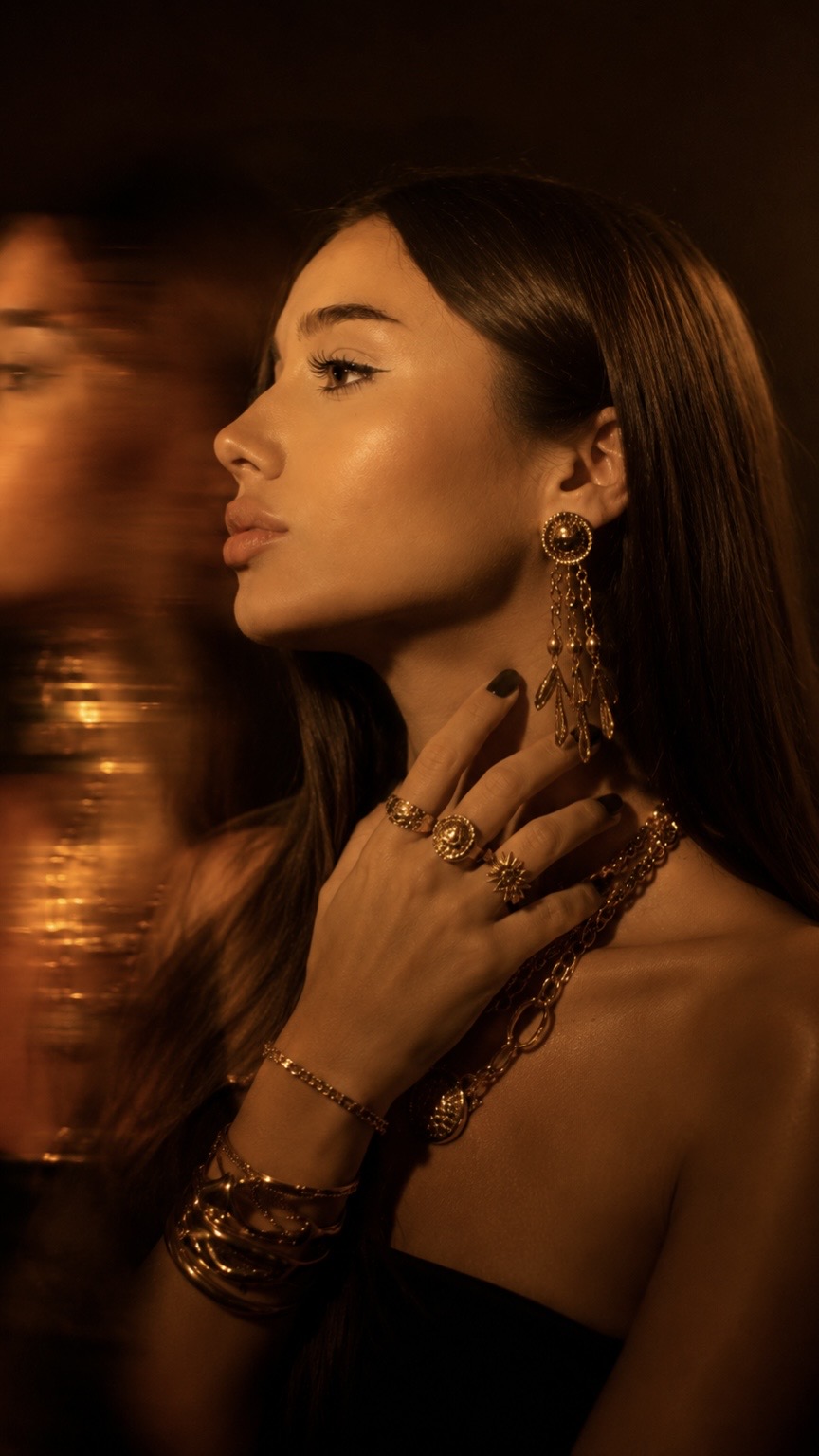 Golden-lit profile portrait with layered gold jewellery