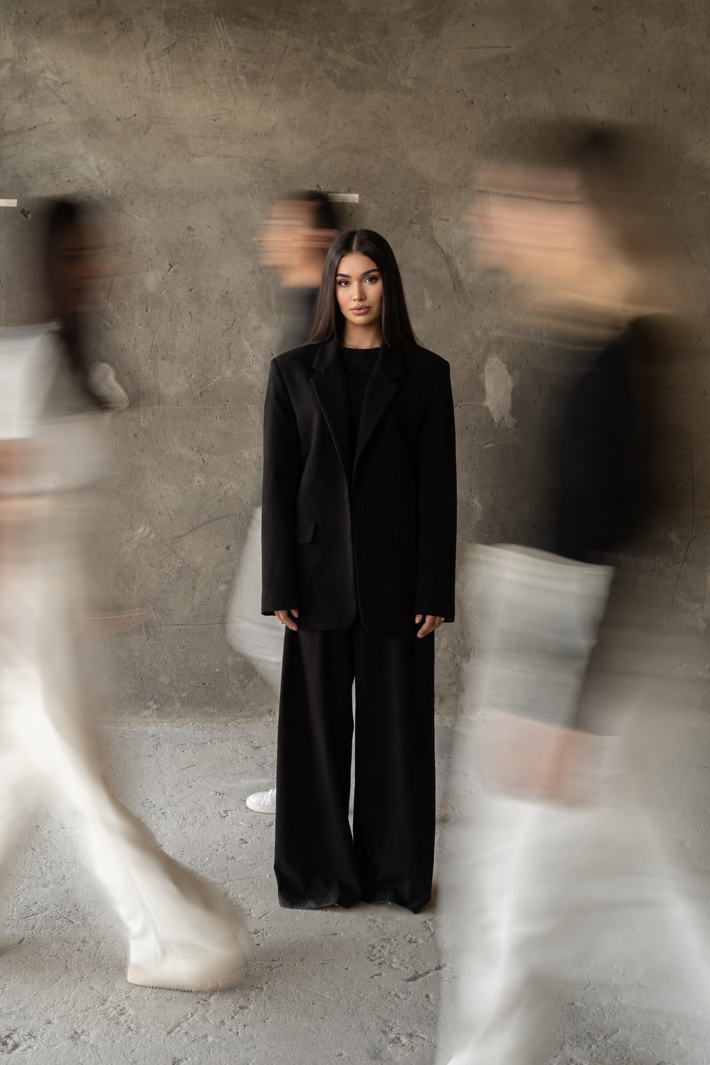 Portrait of Meri Nanijanyan in a black oversized suit with motion-blurred figures around her
